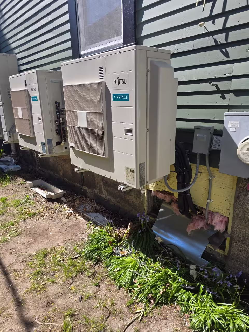 Two outdoor ductless mini split condenser units installed beside a home