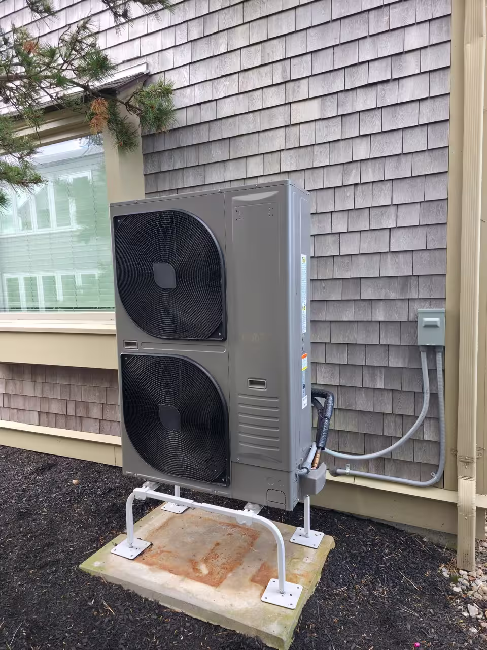 Outdoor heat pump condenser installed beside a home